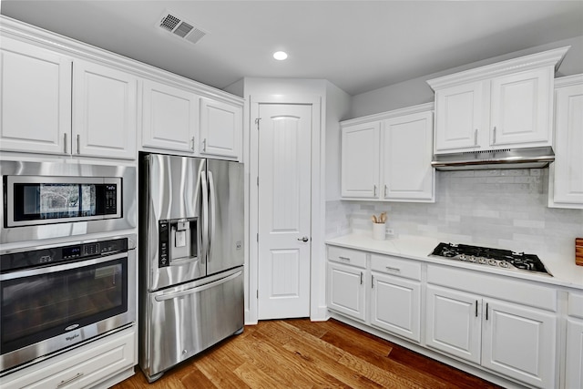 kitchen with light wood-type flooring, appliances with stainless steel finishes, backsplash, and white cabinetry