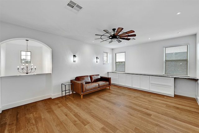 sitting room with ceiling fan with notable chandelier and light wood-type flooring