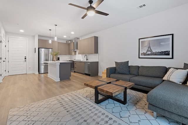 living room with sink, ceiling fan, and light hardwood / wood-style flooring