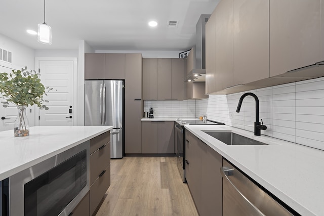 kitchen featuring stainless steel appliances, sink, backsplash, hanging light fixtures, and gray cabinetry