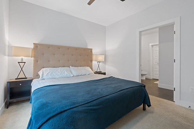 bedroom with ceiling fan, ensuite bathroom, and dark colored carpet