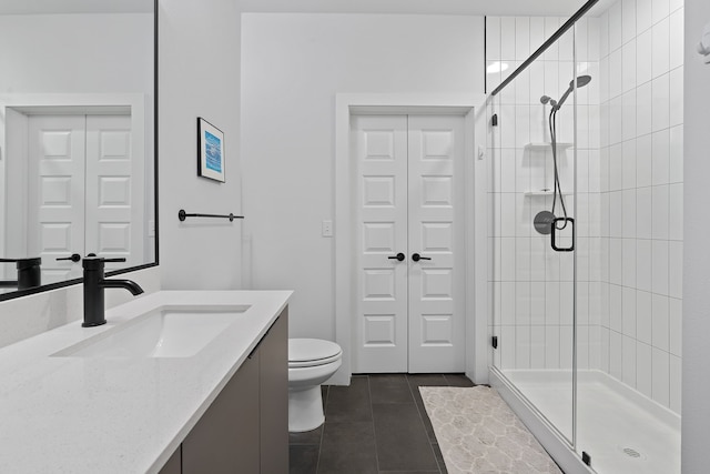 bathroom with toilet, vanity, tile patterned flooring, and a shower with shower door