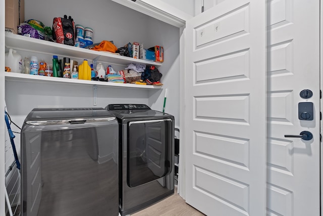 laundry area with washing machine and clothes dryer and light hardwood / wood-style flooring