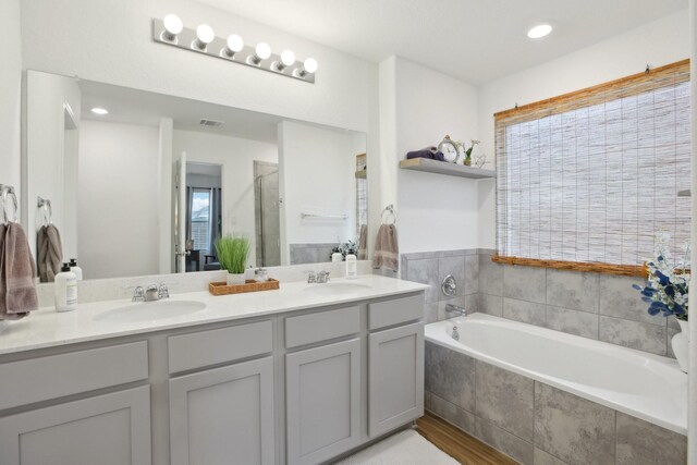 bathroom with independent shower and bath, a healthy amount of sunlight, and vanity