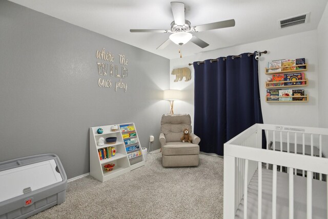 bedroom with a crib, carpet floors, and ceiling fan