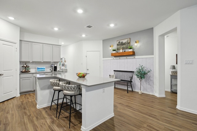 kitchen with sink, kitchen peninsula, a breakfast bar area, a kitchen island, and dark hardwood / wood-style flooring