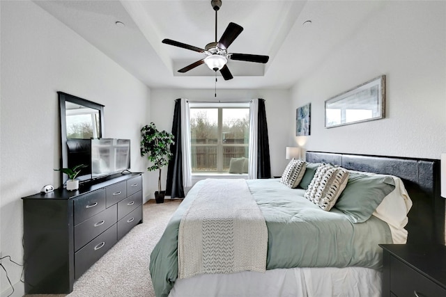 bedroom featuring ceiling fan, a tray ceiling, and light colored carpet