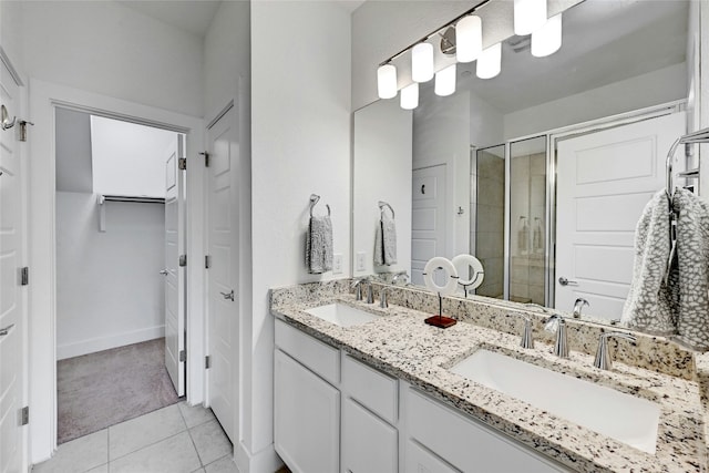 bathroom featuring a stall shower, a walk in closet, a sink, and double vanity