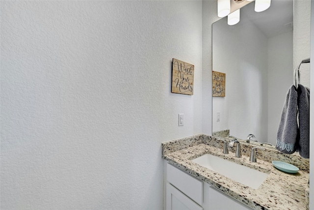 bathroom with a textured wall and vanity