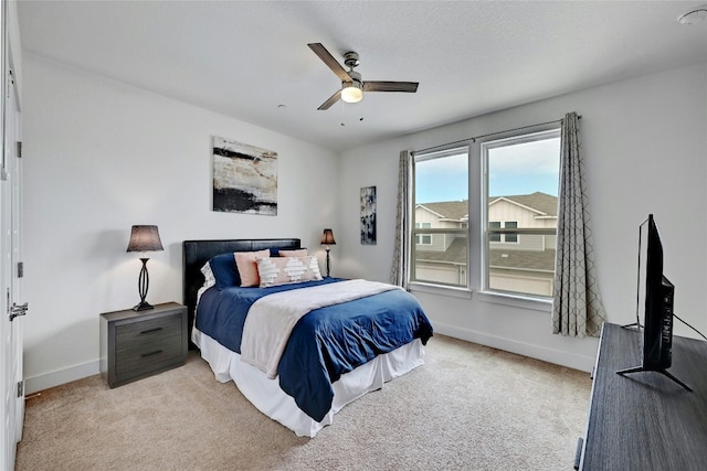 bedroom featuring light colored carpet, ceiling fan, a textured ceiling, and baseboards