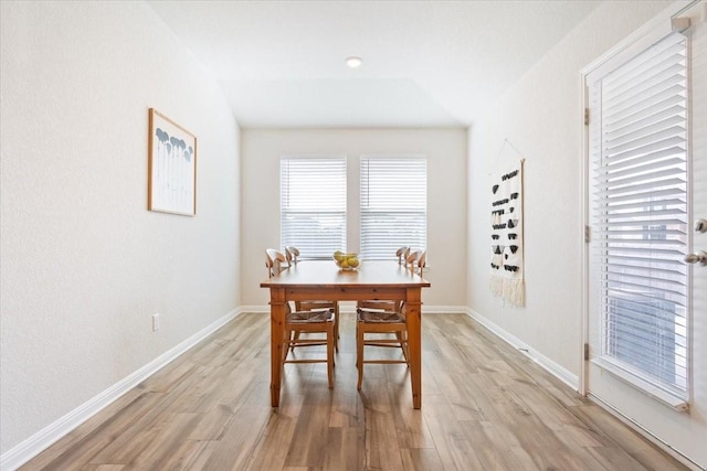 dining area featuring light wood-type flooring and vaulted ceiling