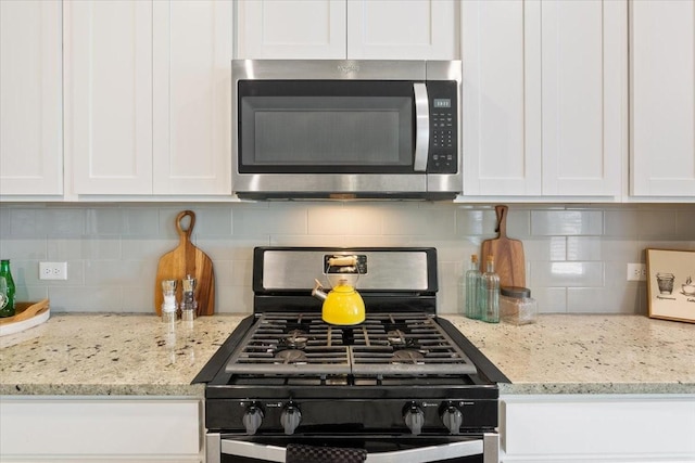 kitchen featuring stainless steel appliances, backsplash, and white cabinets