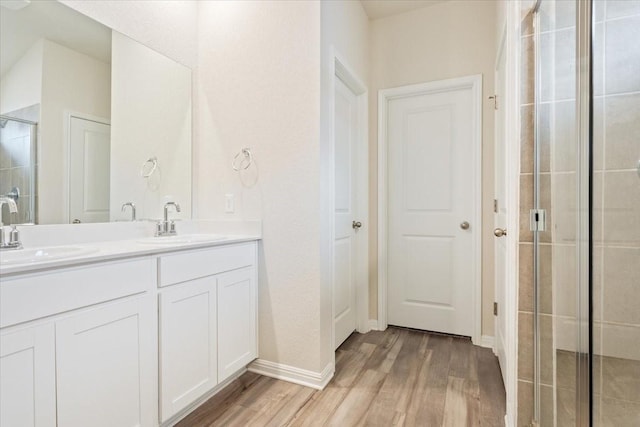 bathroom with a shower with shower door, wood-type flooring, and vanity