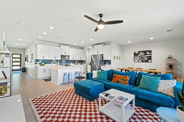 living room featuring ceiling fan, light tile patterned flooring, and sink