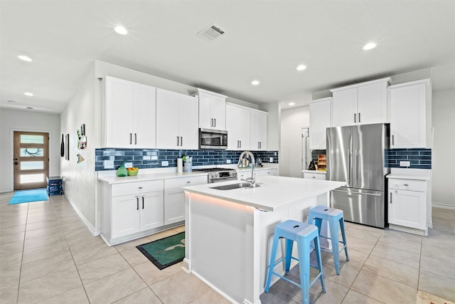 kitchen with sink, white cabinetry, a center island with sink, a breakfast bar, and appliances with stainless steel finishes