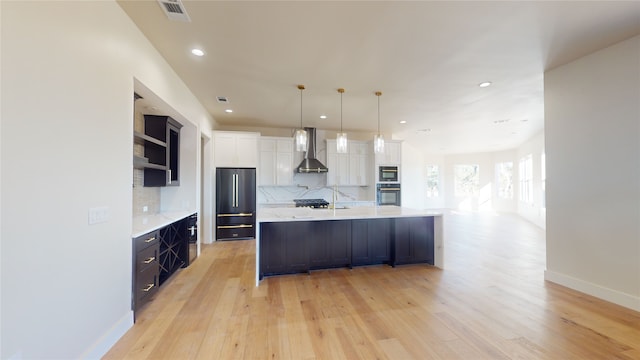 kitchen with a spacious island, high end refrigerator, decorative backsplash, wall chimney exhaust hood, and black oven