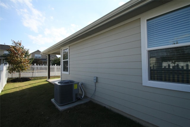 view of side of property with central air condition unit and a lawn