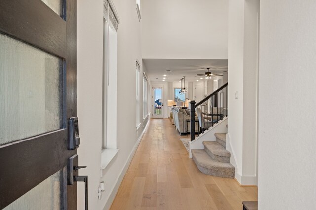 entrance foyer with light wood-type flooring, ceiling fan, and a towering ceiling