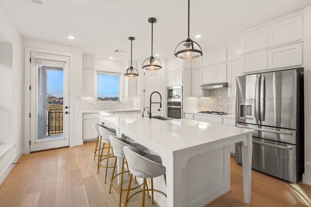 kitchen featuring white cabinetry, a kitchen island with sink, a kitchen breakfast bar, sink, and stainless steel appliances