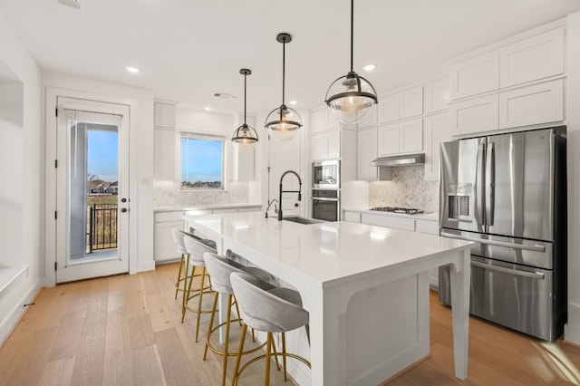 kitchen featuring a sink, white cabinetry, light wood-style floors, and appliances with stainless steel finishes