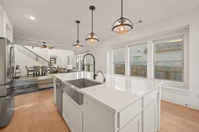 kitchen featuring a sink, stainless steel appliances, white cabinets, visible vents, and light wood-style floors