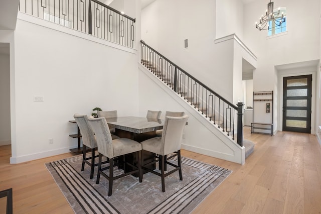117 Dycus Bnd, Liberty Hill, TX 78642 - dining area featuring a high ceiling, wood finished floors, stairs, a chandelier, and baseboards
