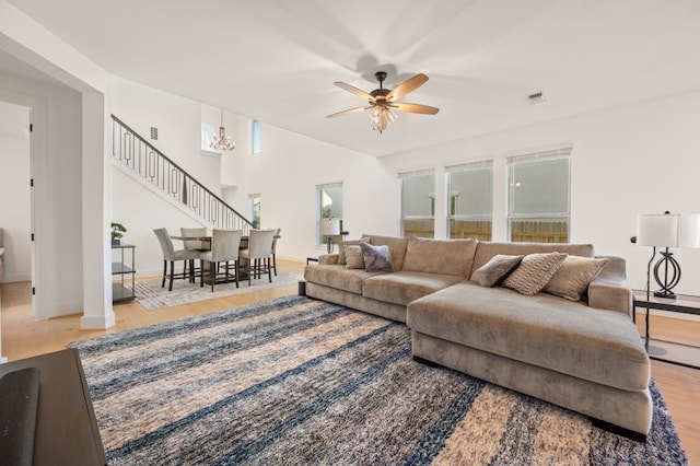 living room with stairs, visible vents, ceiling fan, and wood finished floors