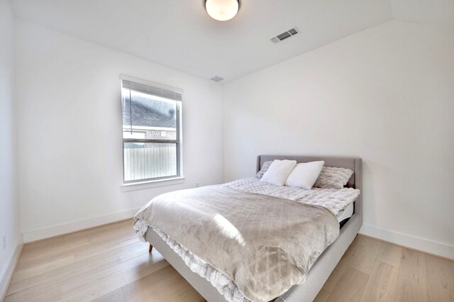 bedroom with light hardwood / wood-style floors and vaulted ceiling