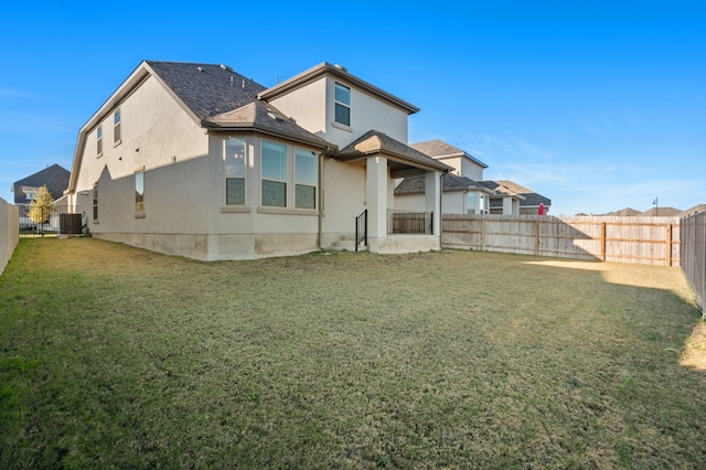 back of property featuring cooling unit, stucco siding, a lawn, and a fenced backyard