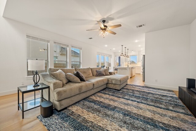 living room featuring sink, ceiling fan, and light hardwood / wood-style flooring