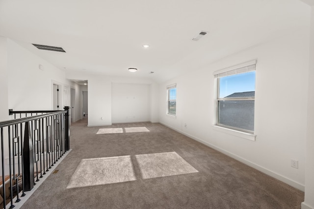 empty room featuring carpet floors, baseboards, and visible vents