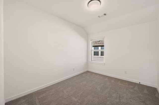 carpeted empty room with vaulted ceiling, baseboards, and visible vents