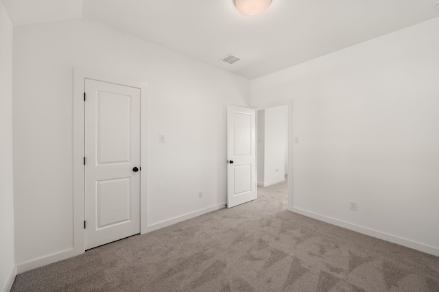 carpeted spare room with vaulted ceiling