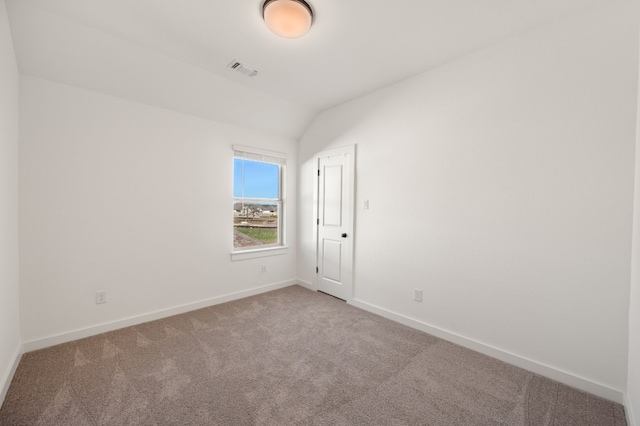 empty room featuring lofted ceiling, carpet, baseboards, and visible vents