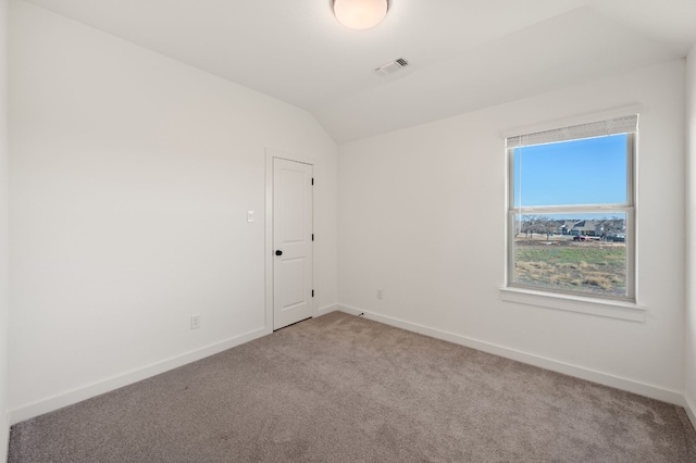 empty room with lofted ceiling, carpet, baseboards, and visible vents