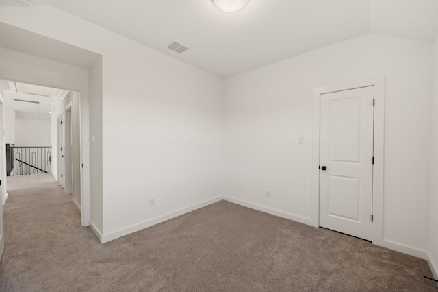 carpeted spare room with lofted ceiling