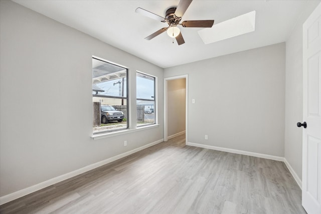 unfurnished room featuring light wood-type flooring, a skylight, and ceiling fan