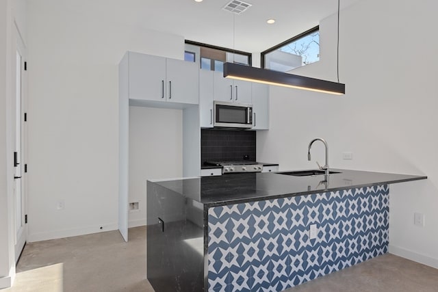 kitchen with sink, decorative backsplash, range, and kitchen peninsula