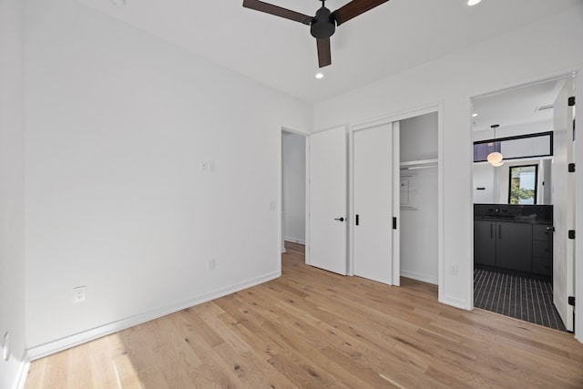 unfurnished bedroom featuring connected bathroom, a closet, ceiling fan, and light hardwood / wood-style flooring