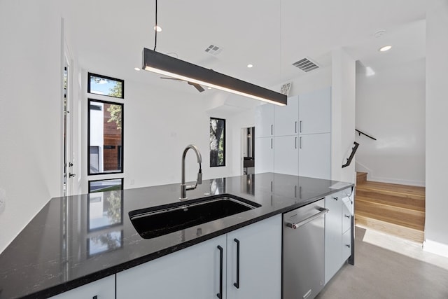 kitchen with white cabinets, dark stone countertops, a wealth of natural light, and sink