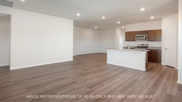 kitchen featuring dark wood-type flooring, stainless steel appliances, a center island with sink, and sink