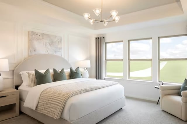 bedroom with carpet floors, a tray ceiling, and an inviting chandelier