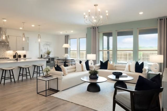 living room featuring light wood-type flooring, sink, and a notable chandelier