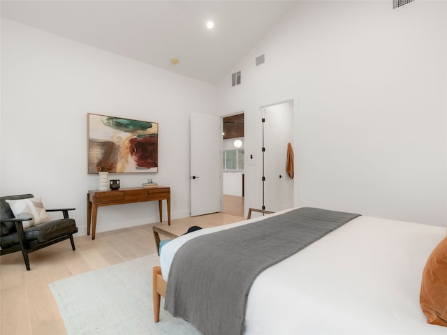 bedroom with high vaulted ceiling and light wood-type flooring