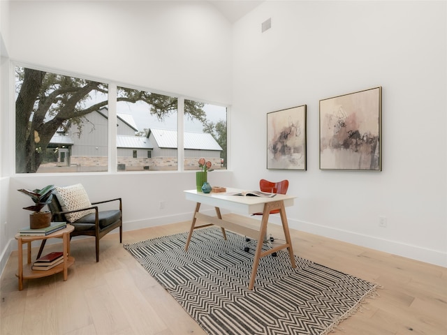 office area featuring a high ceiling, plenty of natural light, and light hardwood / wood-style flooring