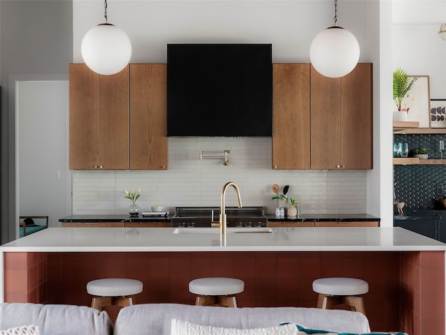 kitchen with a kitchen breakfast bar, decorative backsplash, and hanging light fixtures