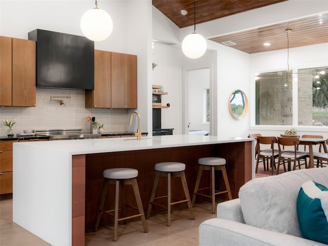 kitchen featuring wood ceiling, a center island with sink, hanging light fixtures, a kitchen bar, and extractor fan