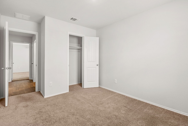 unfurnished bedroom with a closet and light carpet