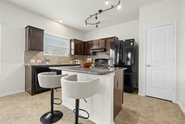 kitchen featuring tasteful backsplash, dark brown cabinets, a kitchen island, a breakfast bar, and black appliances