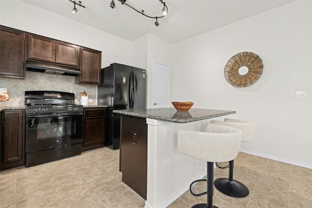 kitchen with a breakfast bar area, backsplash, a kitchen island, dark brown cabinetry, and black appliances